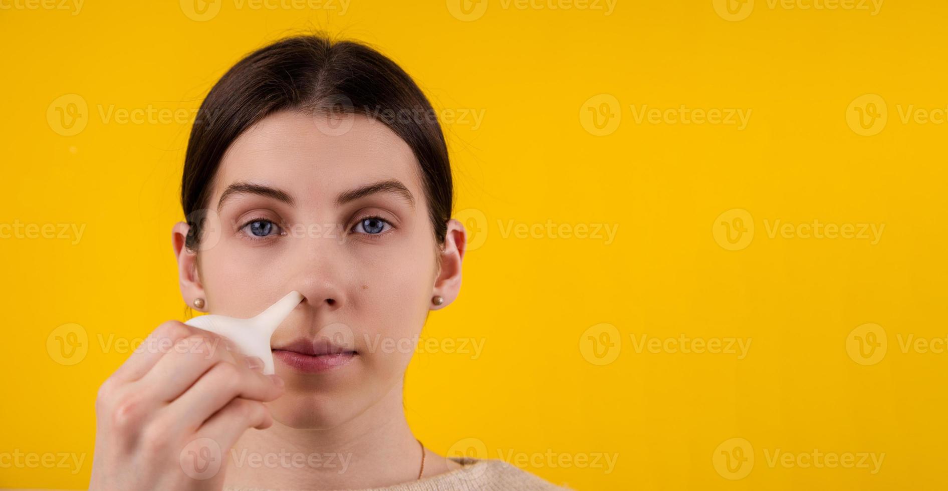 Woman cleaning Her blocked nose with a blue rubber nose pump photo