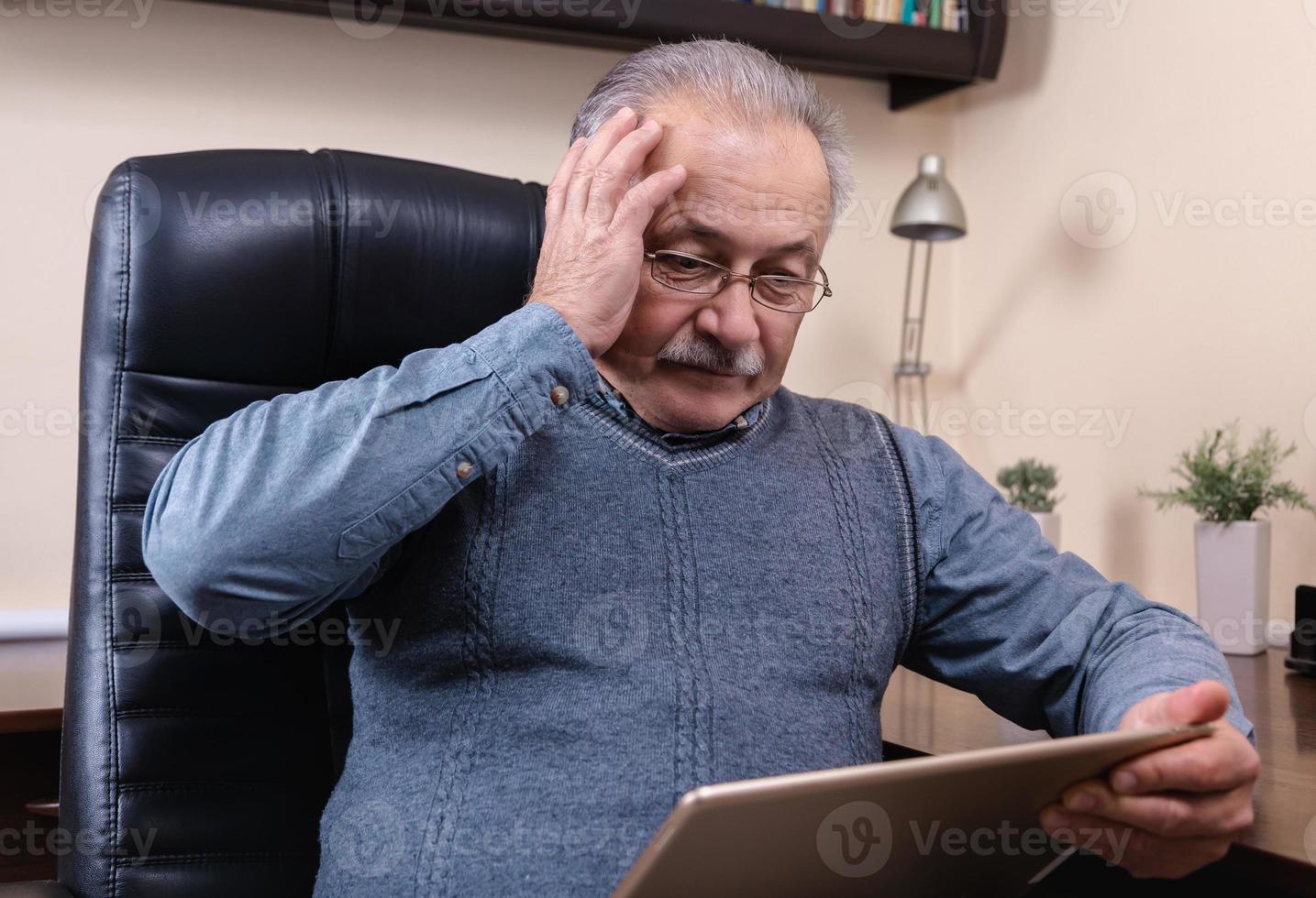 Senior man reading news on digital tablet photo