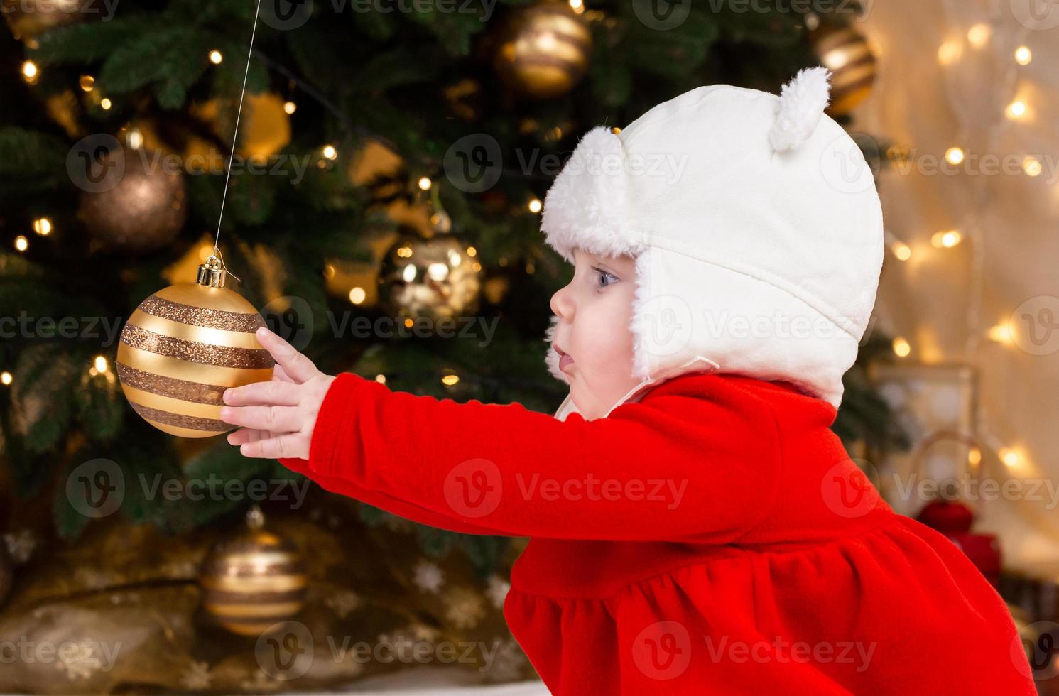 el bebé alcanza una bola de árbol de navidad foto