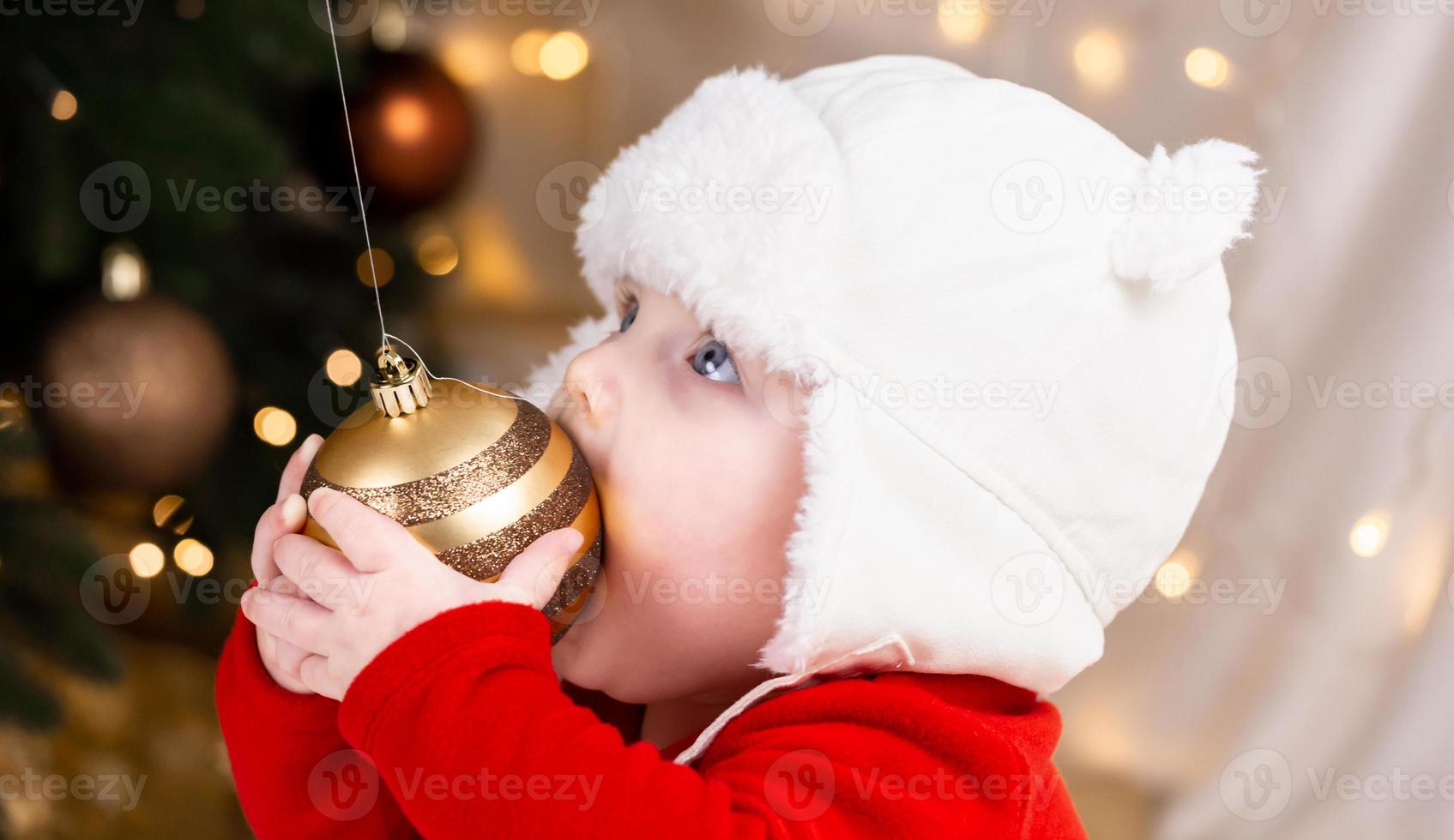 bebé sostiene una bola de navidad foto