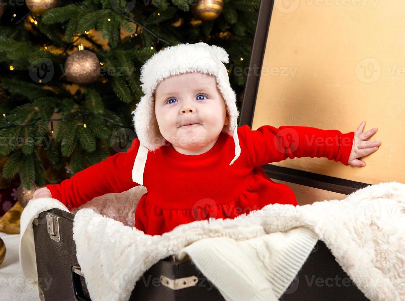 The baby is sitting in an old suitcase photo