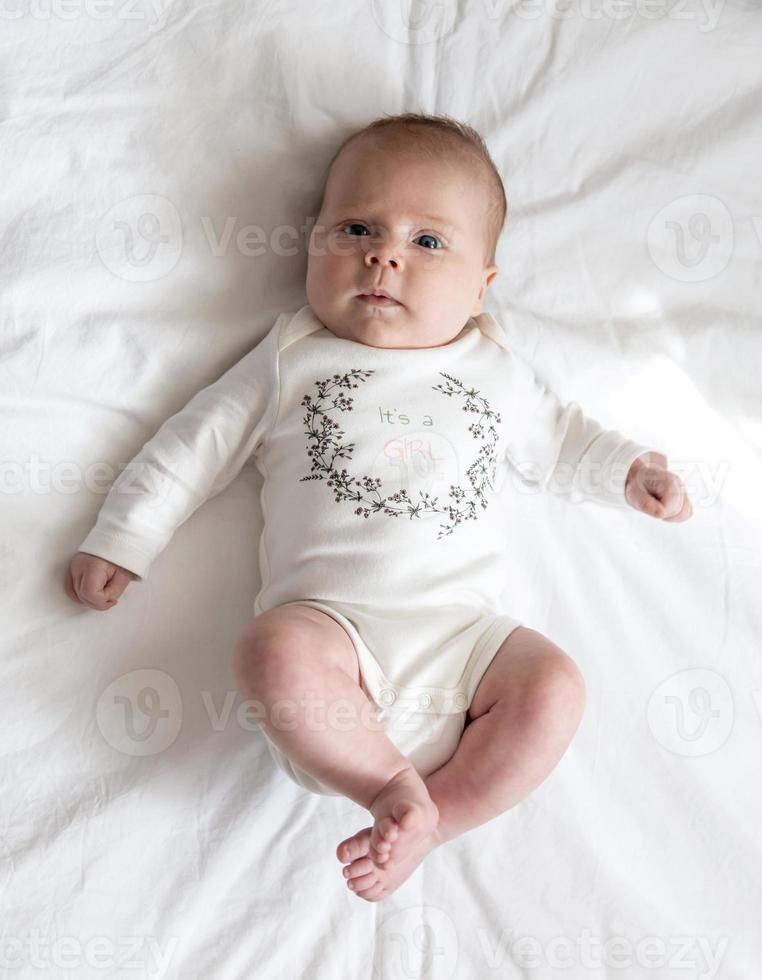 Portrait of a newborn baby girl who lies on a bed photo