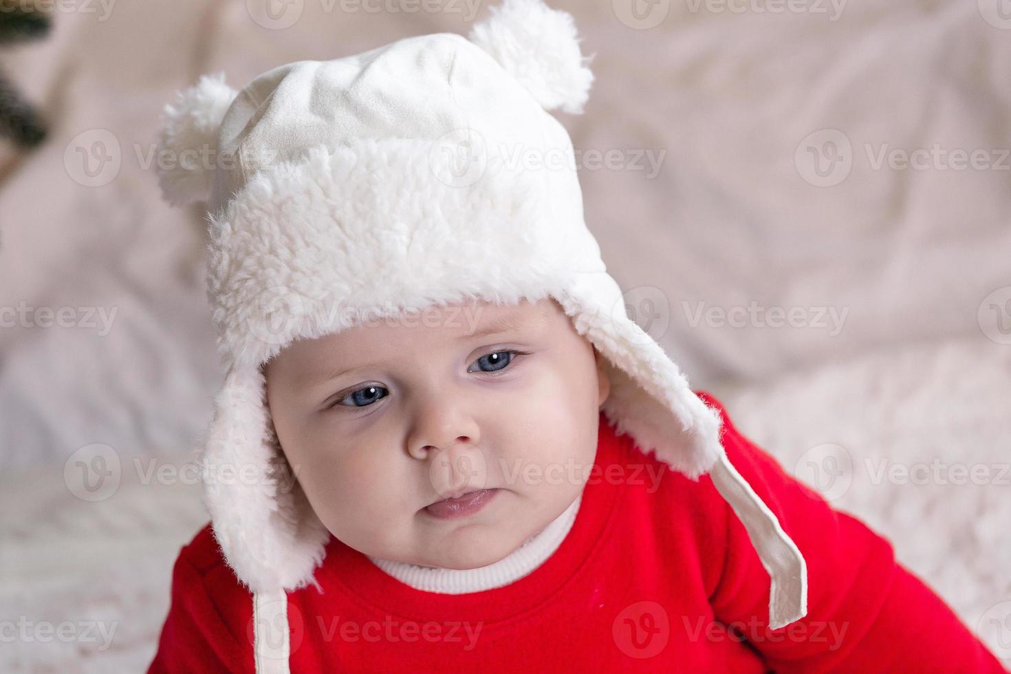 A cute little girl in a red dress and white hat expresses emotions photo