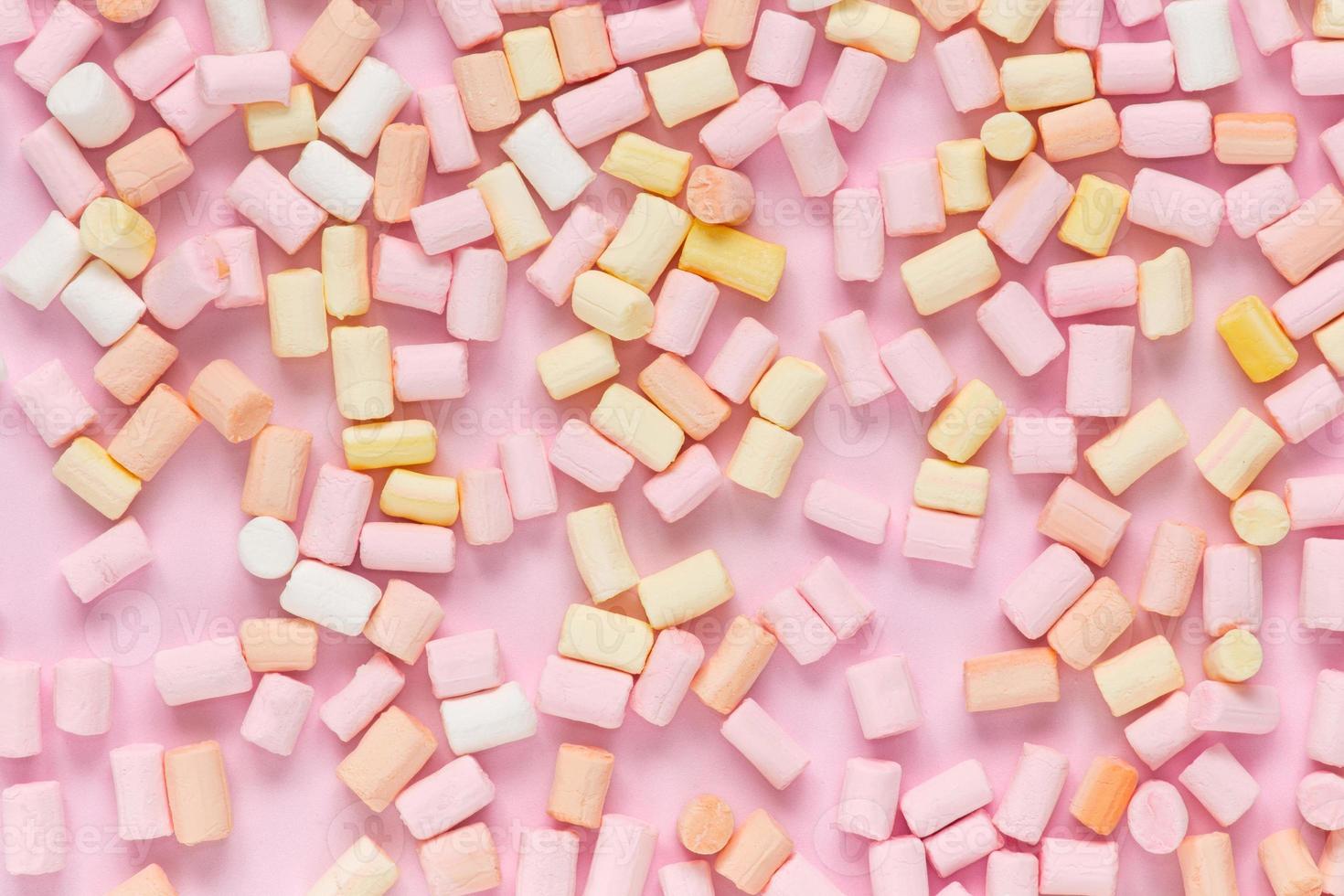 Top view on multicolored marshmallows on a monochrome pink background photo