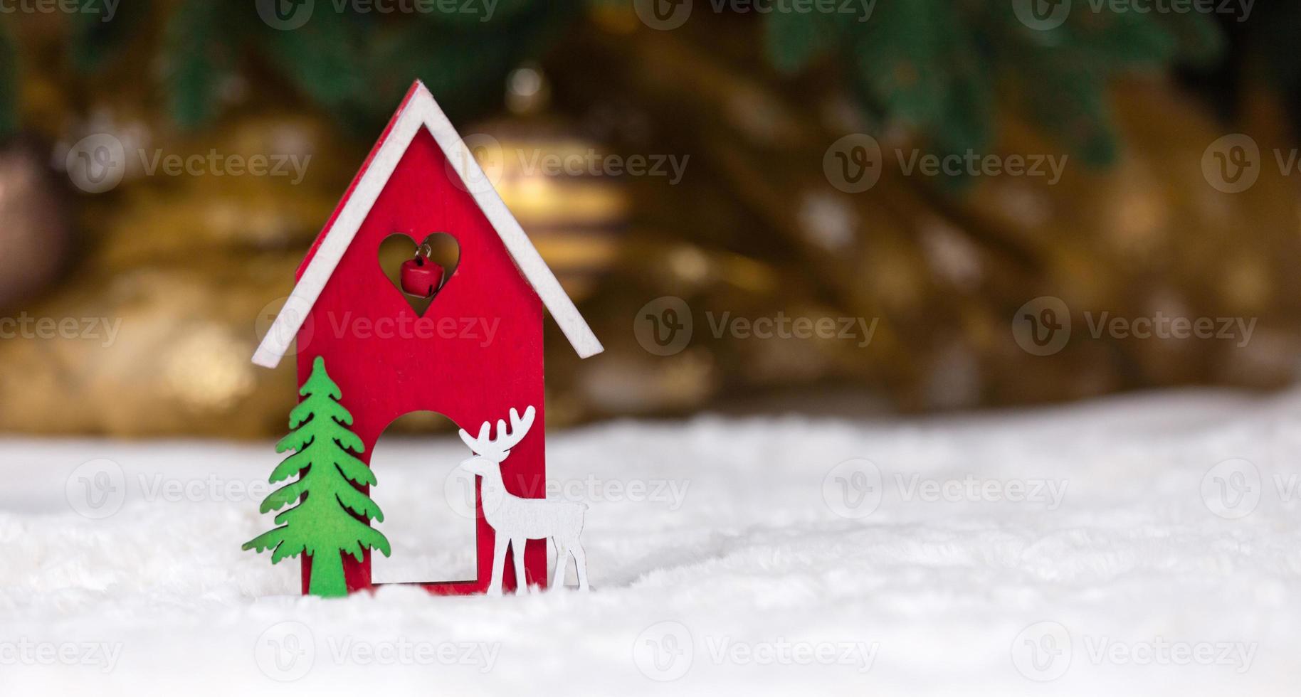 Christmas wooden toy house deer and tree on a white blanket imitating snow photo