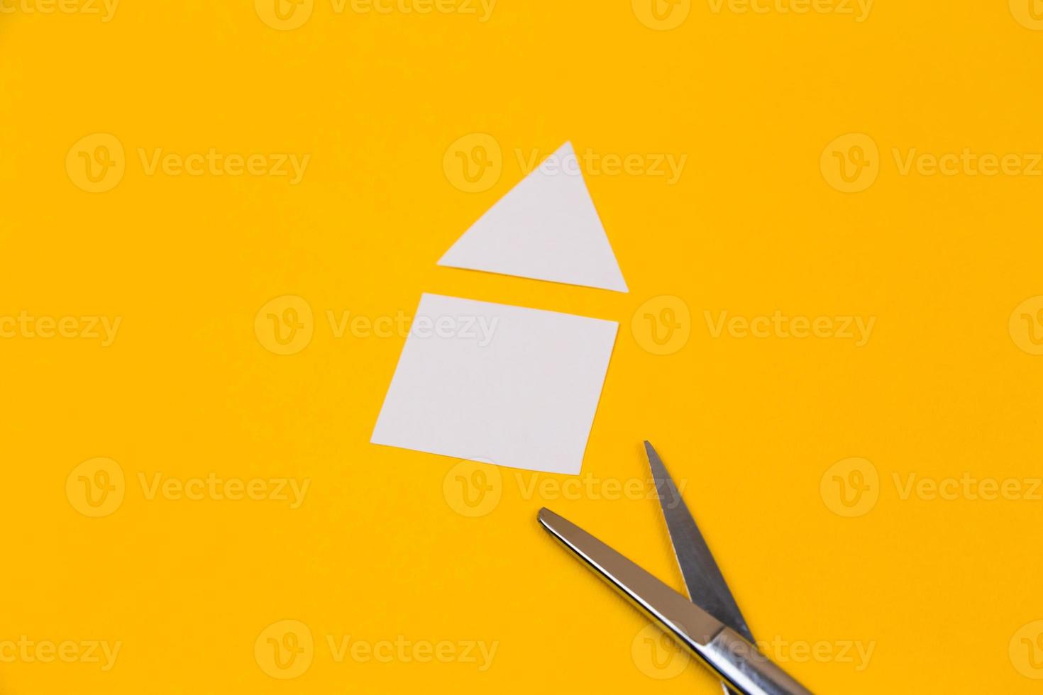 Tijeras y casa cortada de papel sobre el fondo amarillo foto