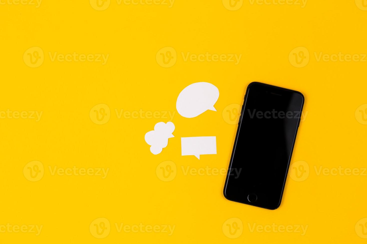 Smartphones with paper speech bubbles on yellow background photo