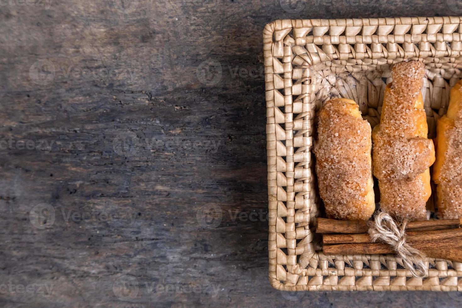 Croissants lie in a wicker basket with cinnamon photo