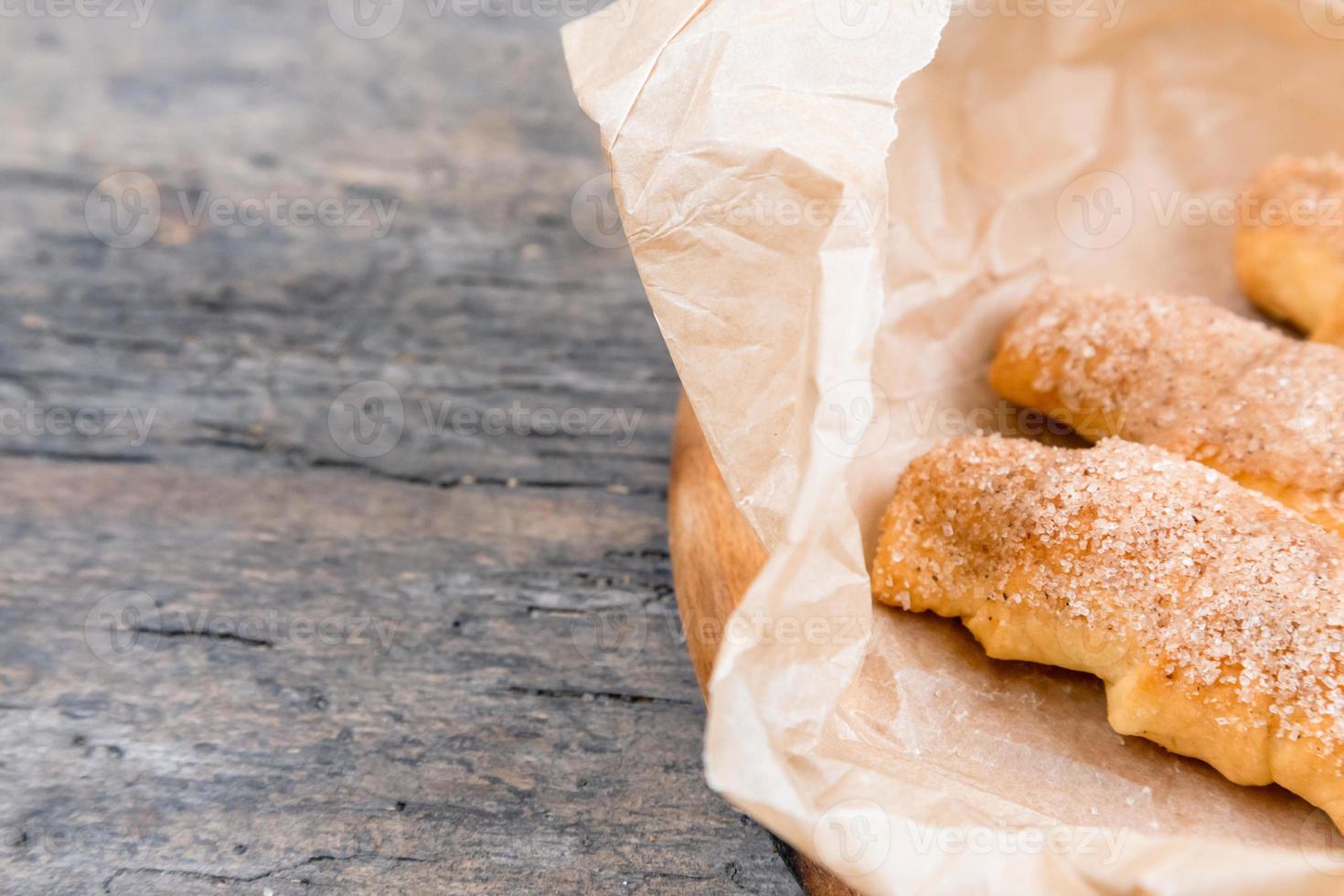 Croissants frescos con canela sobre papel arrugado en la mesa de madera de fondo foto