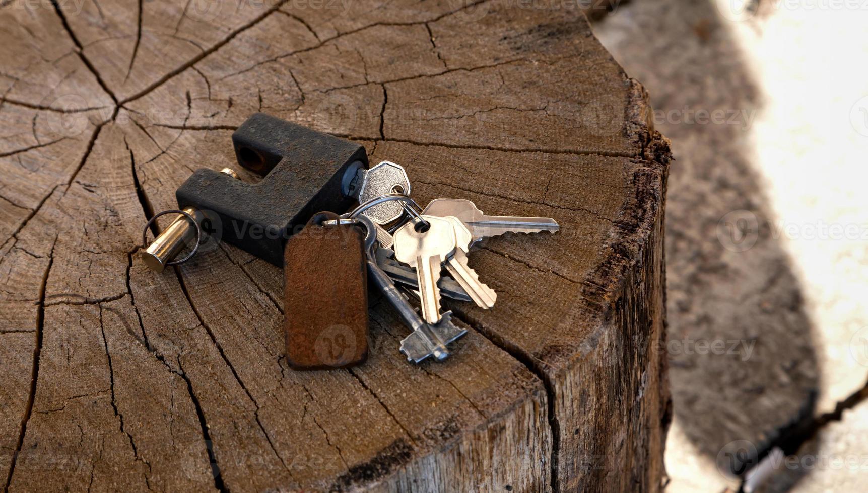A bunch of keys and a padlock lie on a wooden background photo