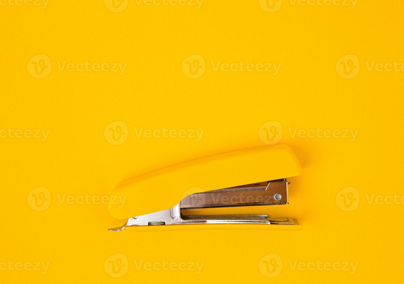 Yellow stapler on yellow background photo