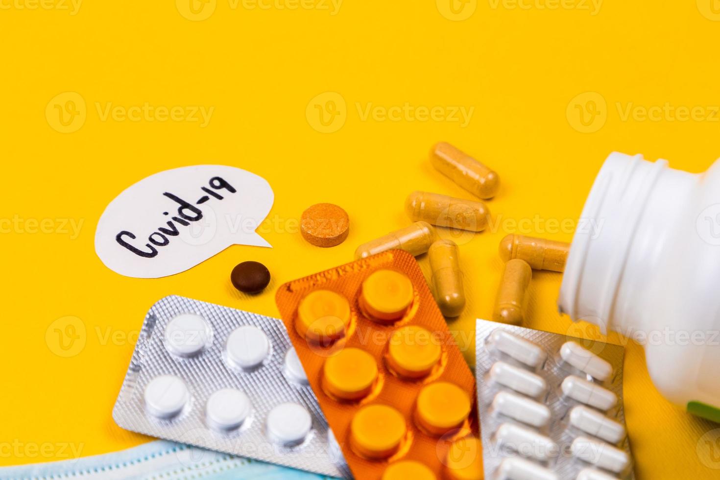 Mascarilla de protección médica de algodón azul sobre un fondo de papel amarillo con pastillas foto