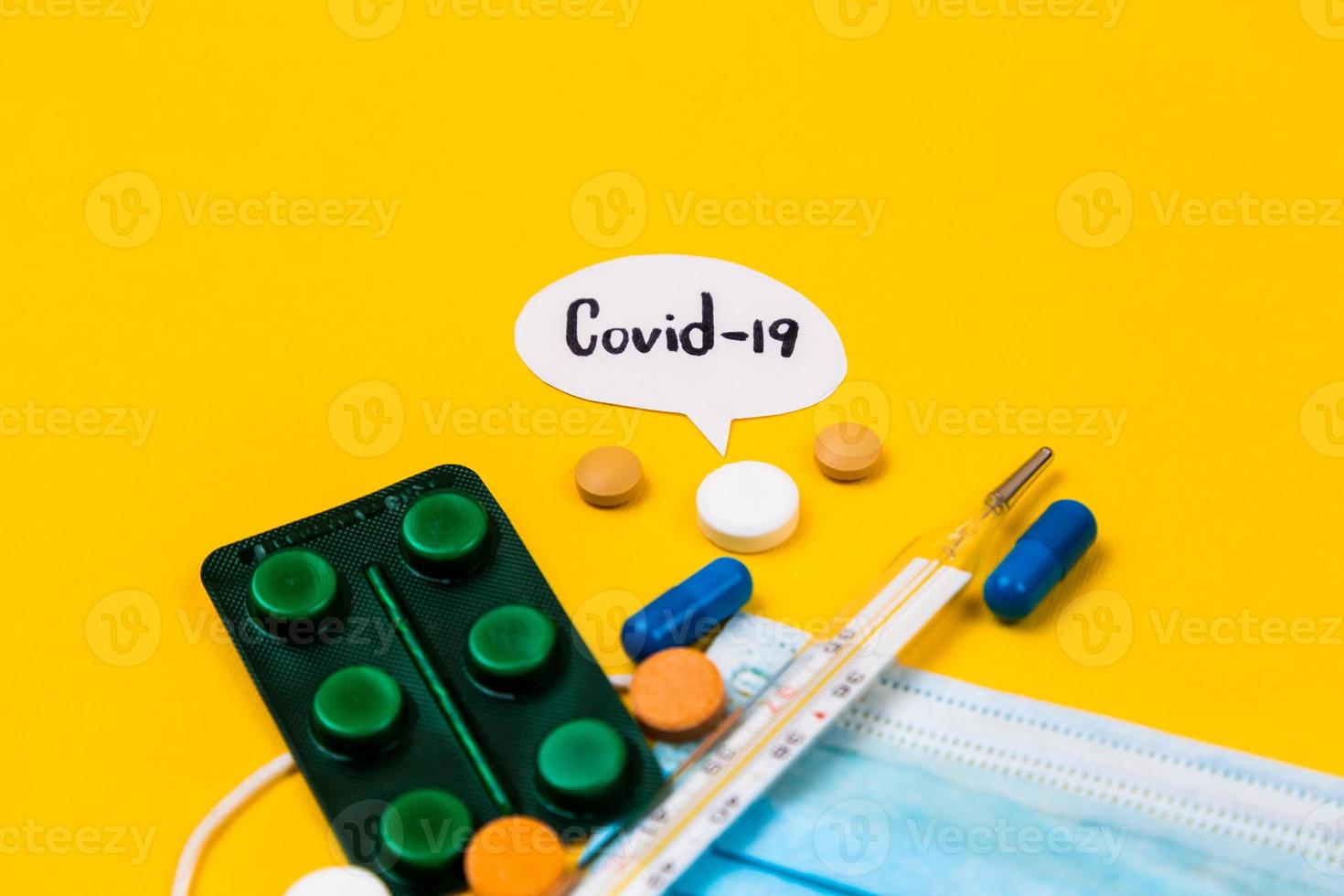 Blue cotton medical protection face mask on a yellow paper background with pills photo