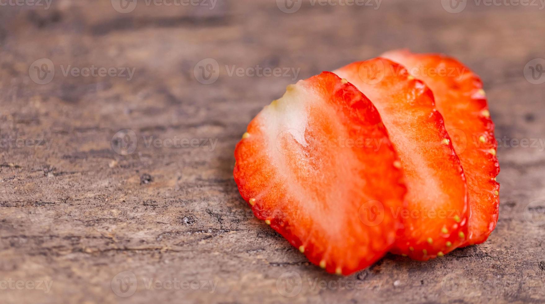 Cut ripe red strawberry on a wooden background photo