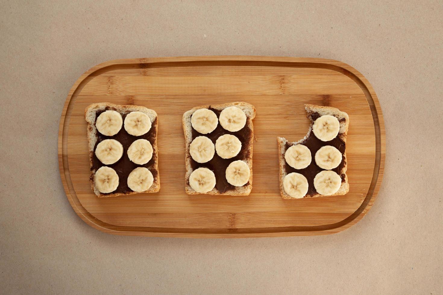 Three banana white bread toasts smeared with chocolate butter photo