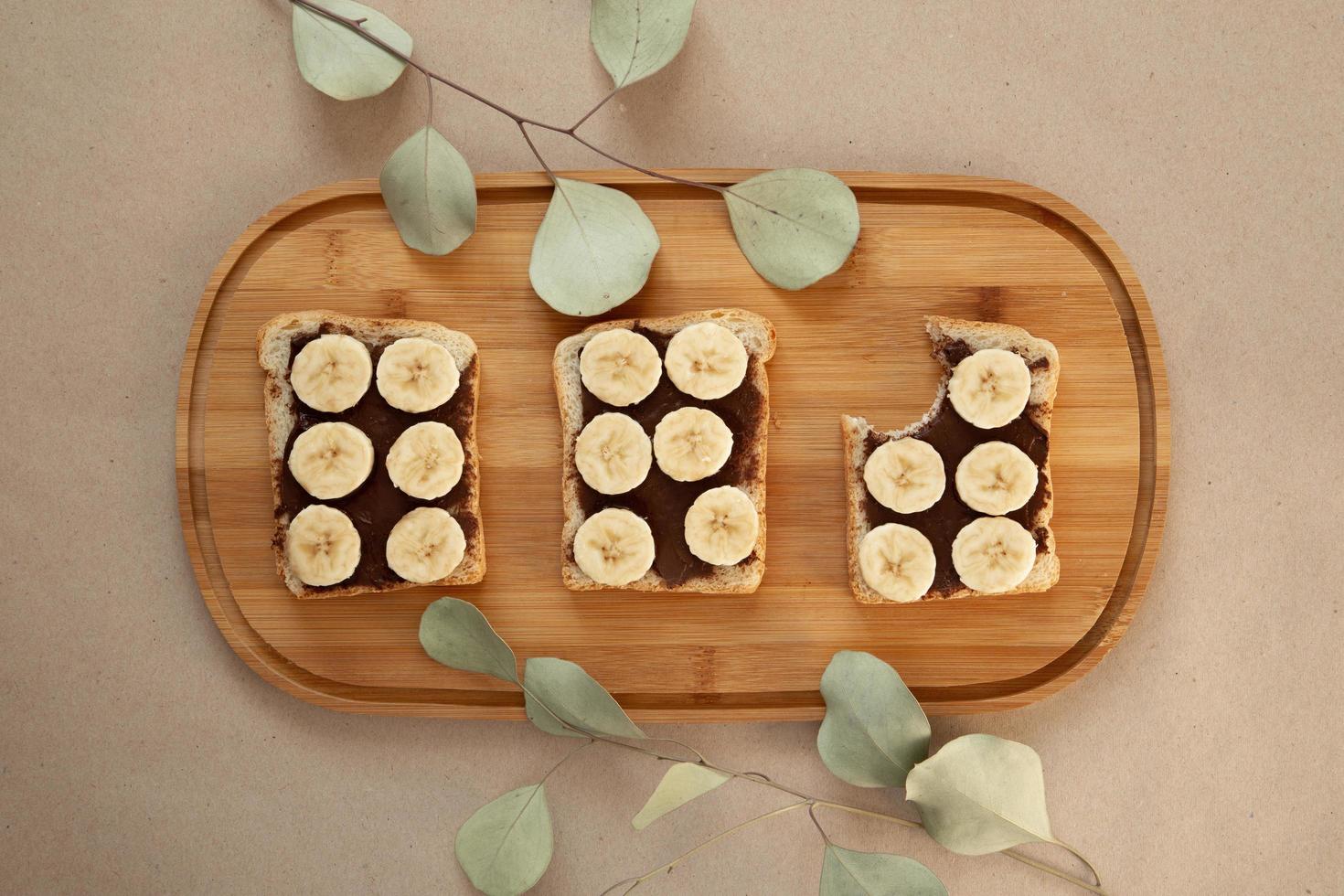 Three banana white bread toasts smeared with chocolate butter photo