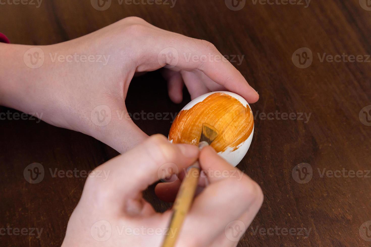 La tradición de las vacaciones de Pascua y el concepto de personas cerca de manos de mujer para colorear huevos de Pascua con colores y pincel foto