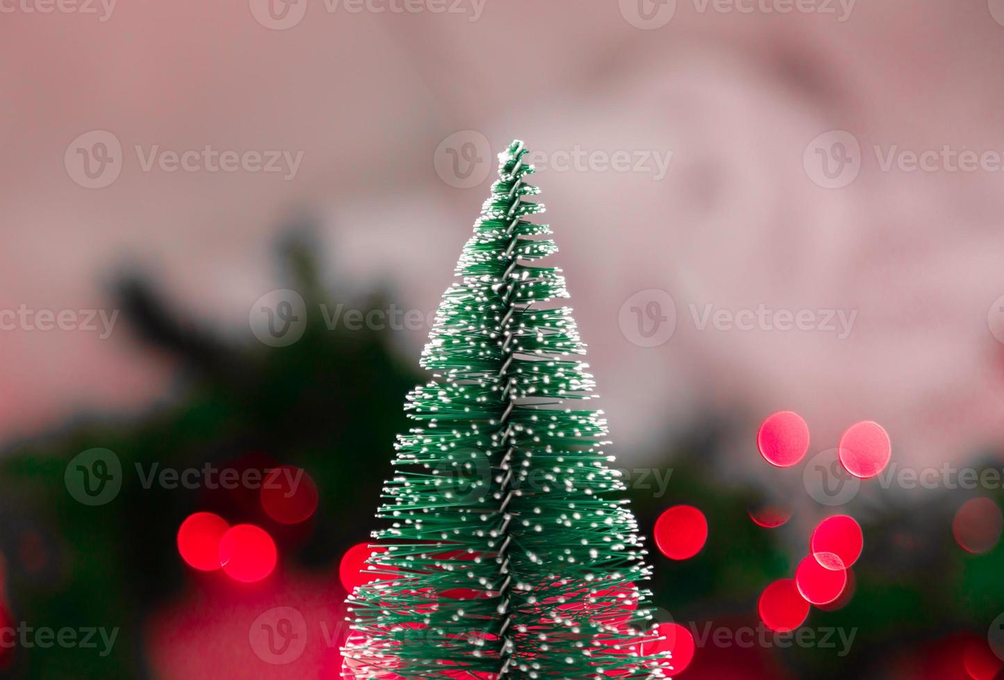 Árbol de Navidad en miniatura en el fondo borroso con luces de Navidad foto