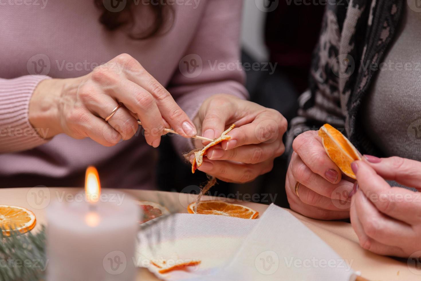 Mujeres haciendo adornos a mano con naranjas secas. foto