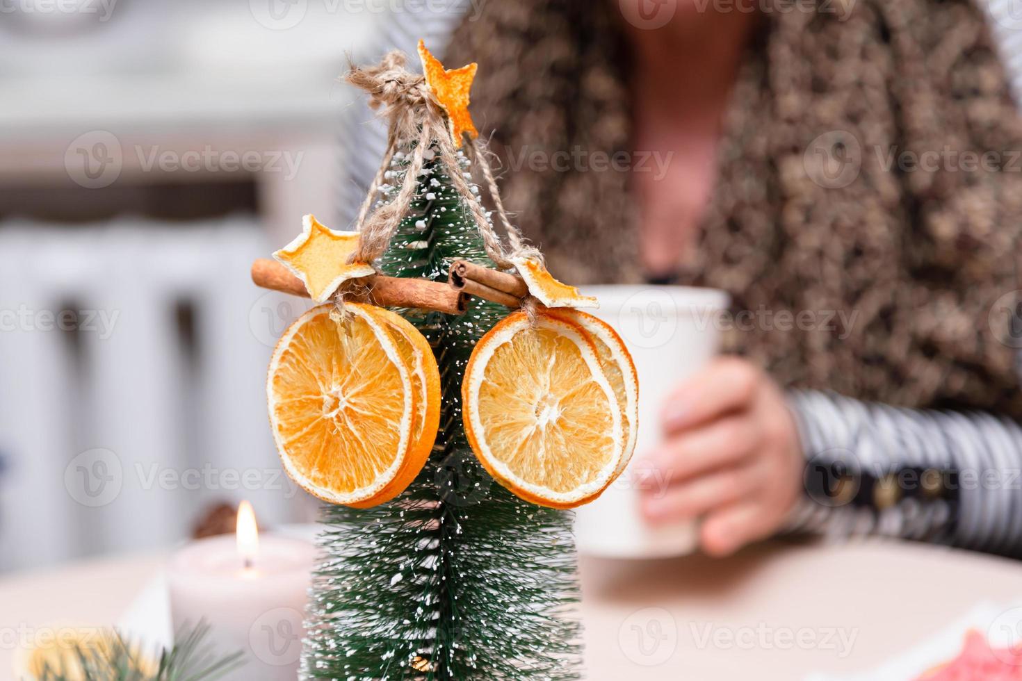 Estrellas anaranjadas secas de mandarina y canela colgando de un árbol de navidad foto