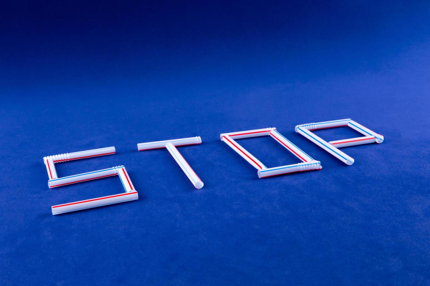 The word STOP made of plastic tubes on a blue background with empty space for text photo