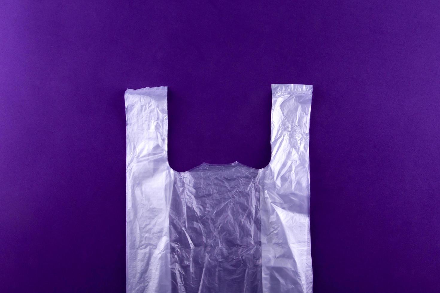 White torn plastic shopping grocery bag on purple background photo