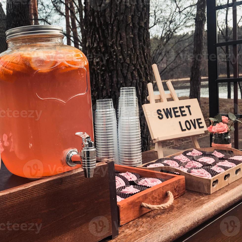 ubicación con bebidas de verano en frascos de vidrio o latas de cupcakes con un cartel que dice dulce amor foto