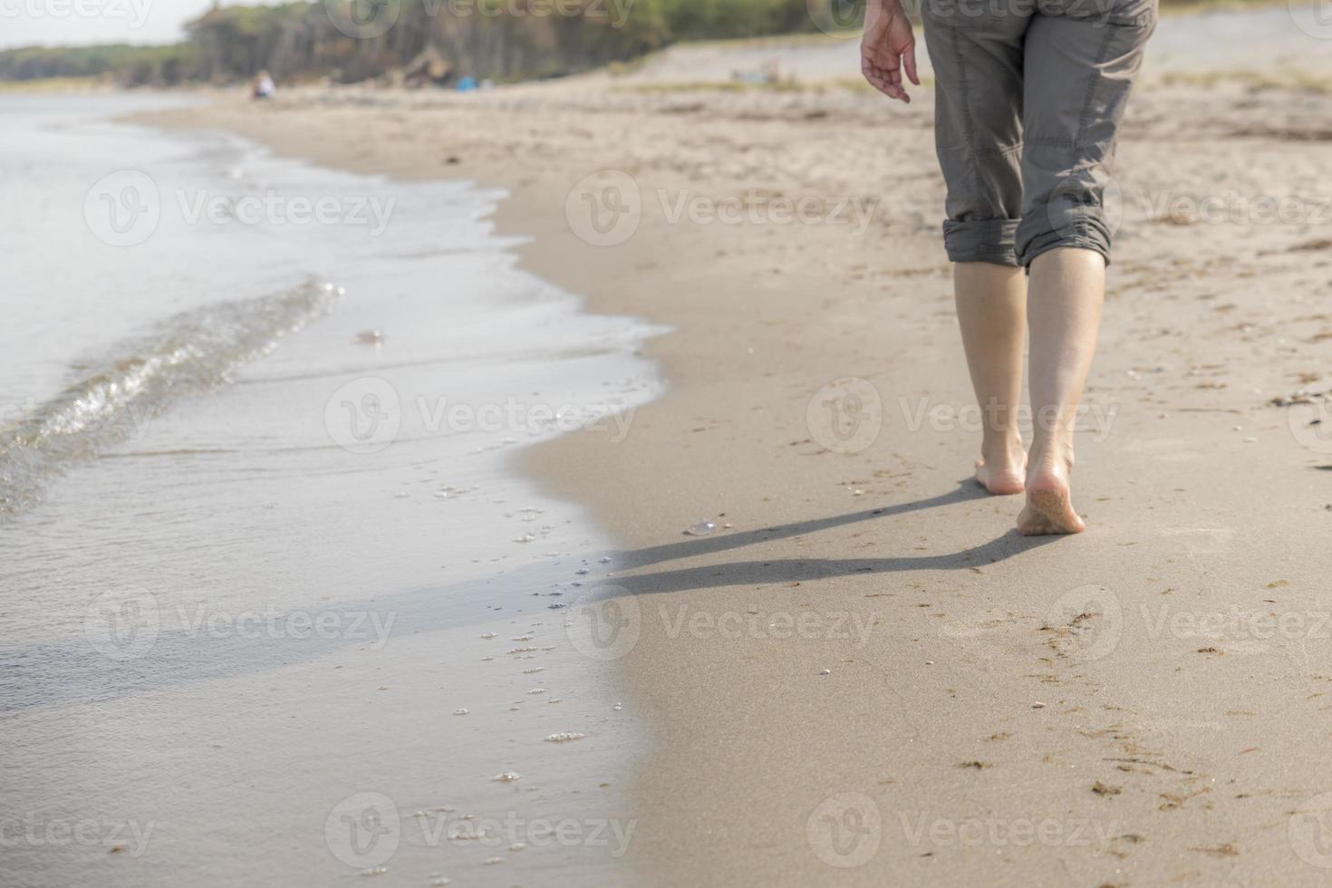 mujer camina por la orilla del mar con áreas borrosas foto