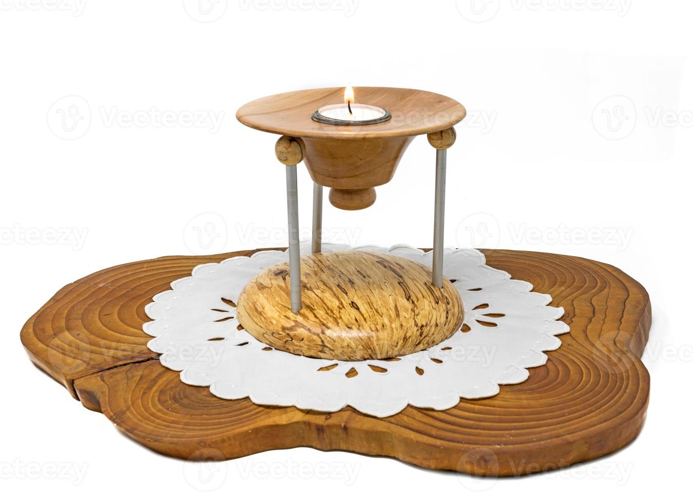 Multi part wooden candlestick with burning candle stands on a dark wooden board photo