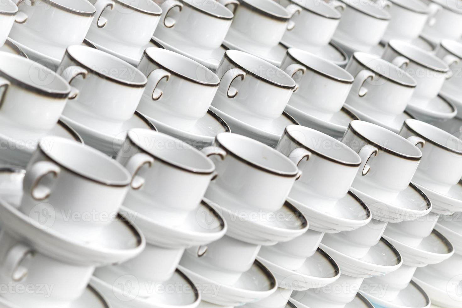 White coffee cups with plates stand stacked in a row photo