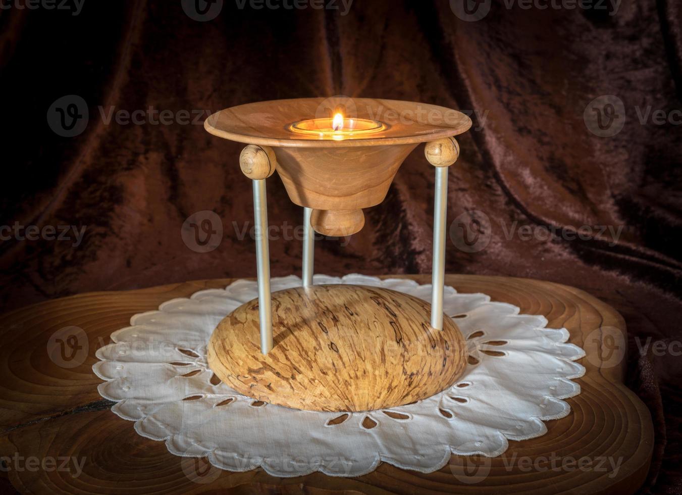 Candelabro de madera de varias partes con velas encendidas se encuentra sobre una tabla de madera oscura. foto