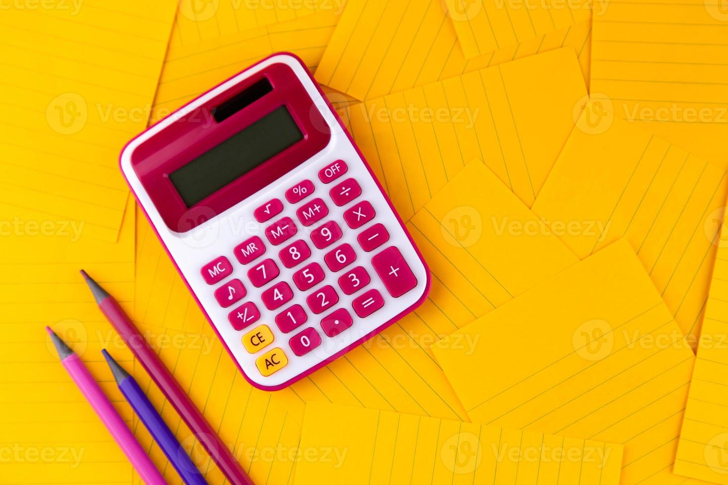 Calculator on orange sheets of paper with pencil photo
