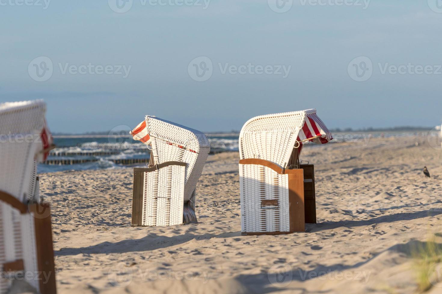 Sillas de playa de pie en la puesta de sol en una playa en el mar Báltico con mar foto