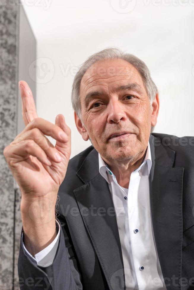 hombre de mediana edad en un traje amenaza su dedo foto