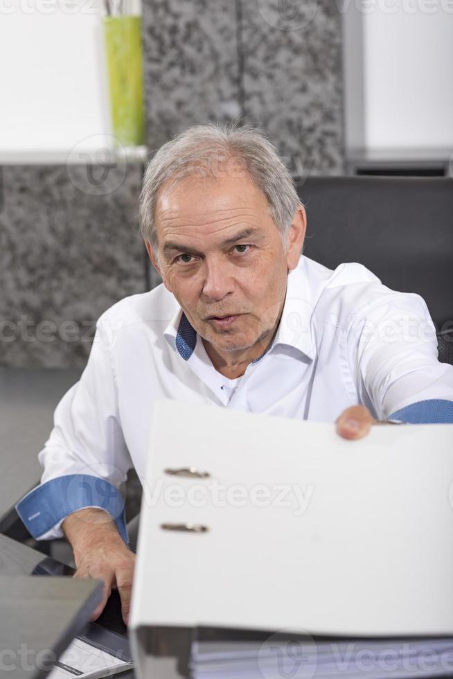 Senior man with a  white shirt hands over a file folder photo