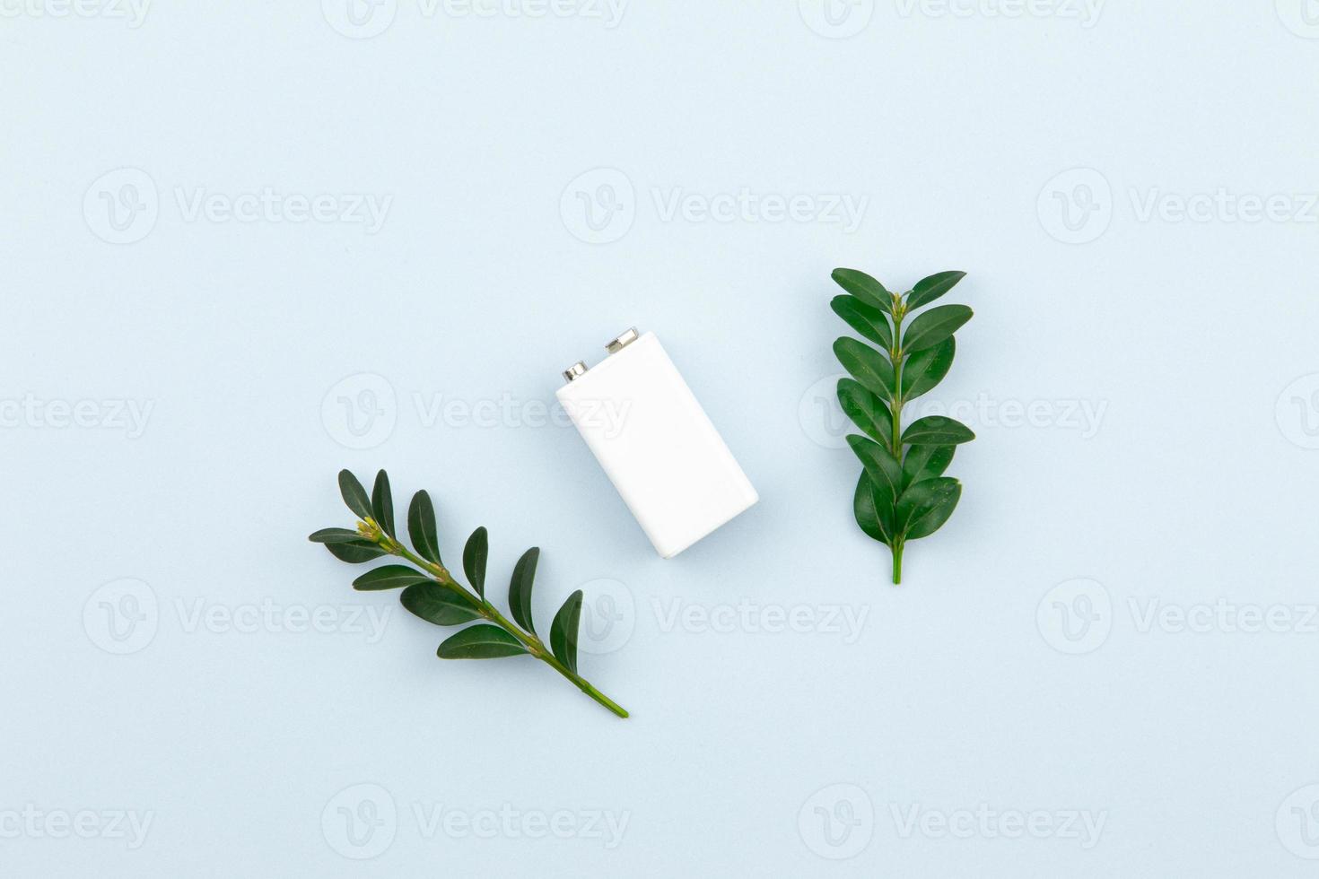 Ilustración de energía ecológica o energía verde con una batería blanca y hojas de ramitas sobre un fondo claro foto