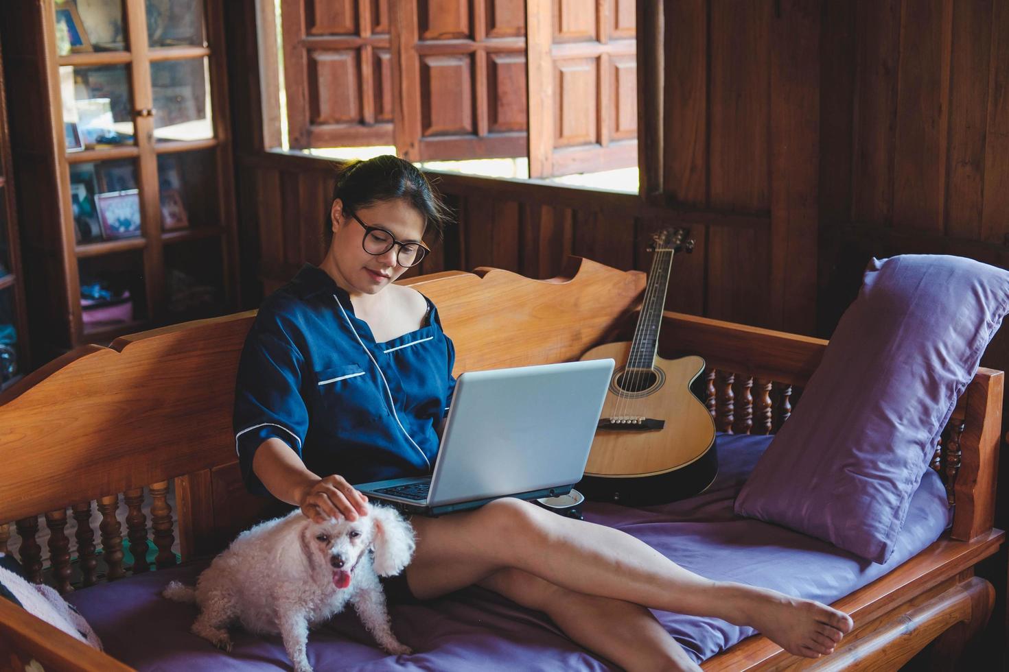 young woman working on laptop at home cute small dog besides work from home photo