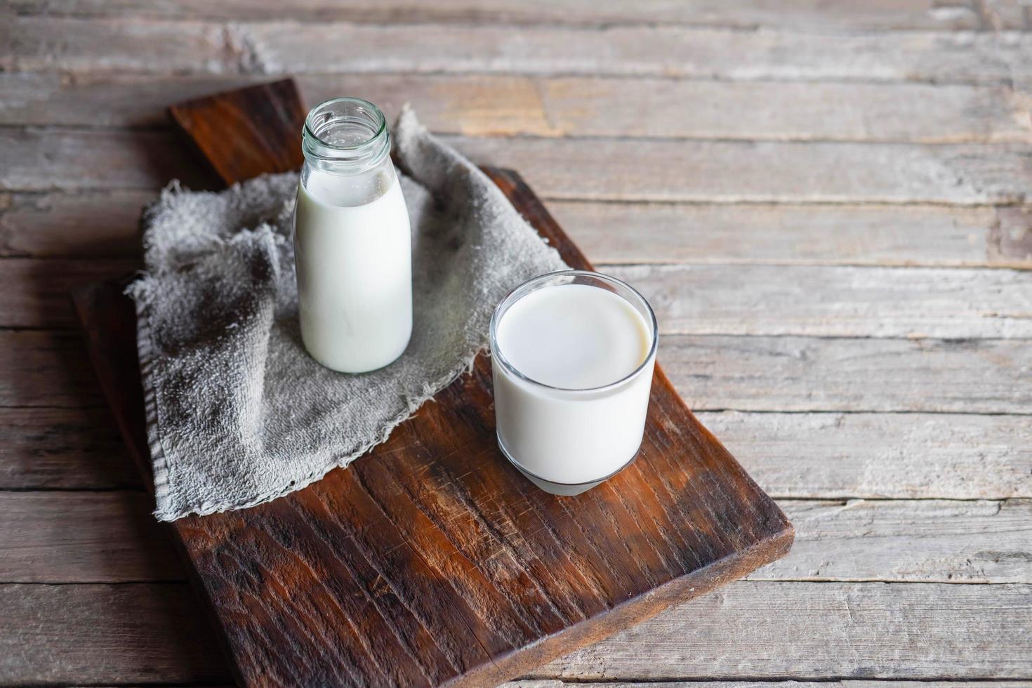 botellas y vasos de leche en una mesa de madera foto