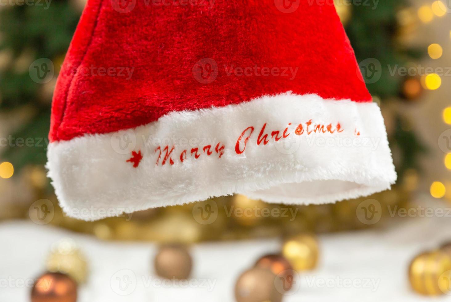 Santa hat with text Merry Christmas on the background of a tree and garlands photo