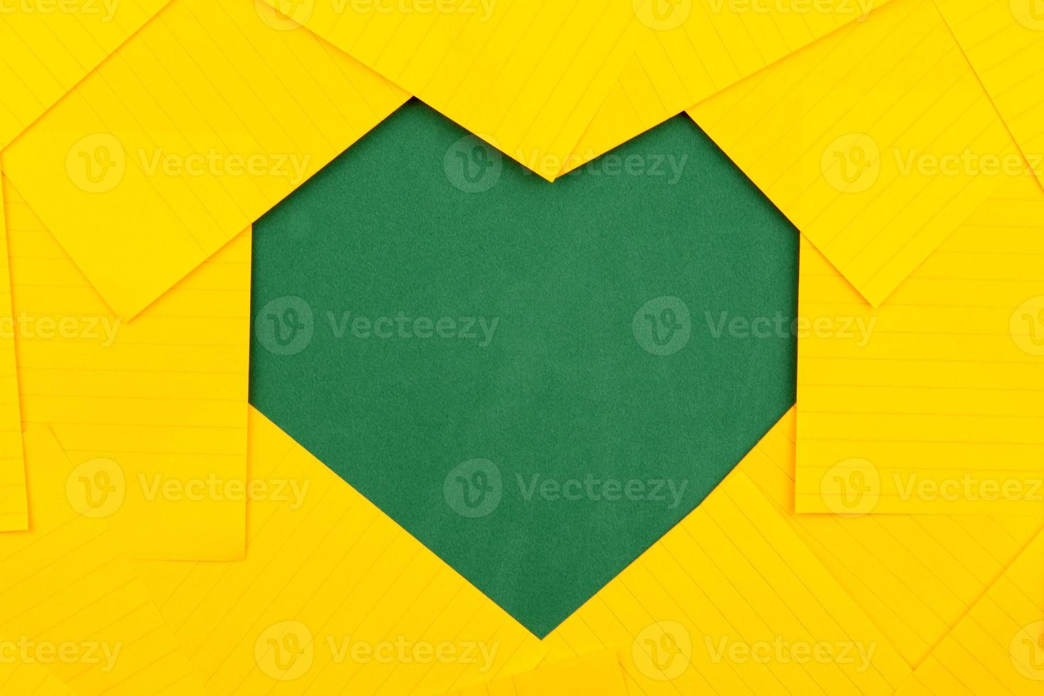 hojas de papel de color naranja en una junta escolar verde forman un marco en forma de corazón foto