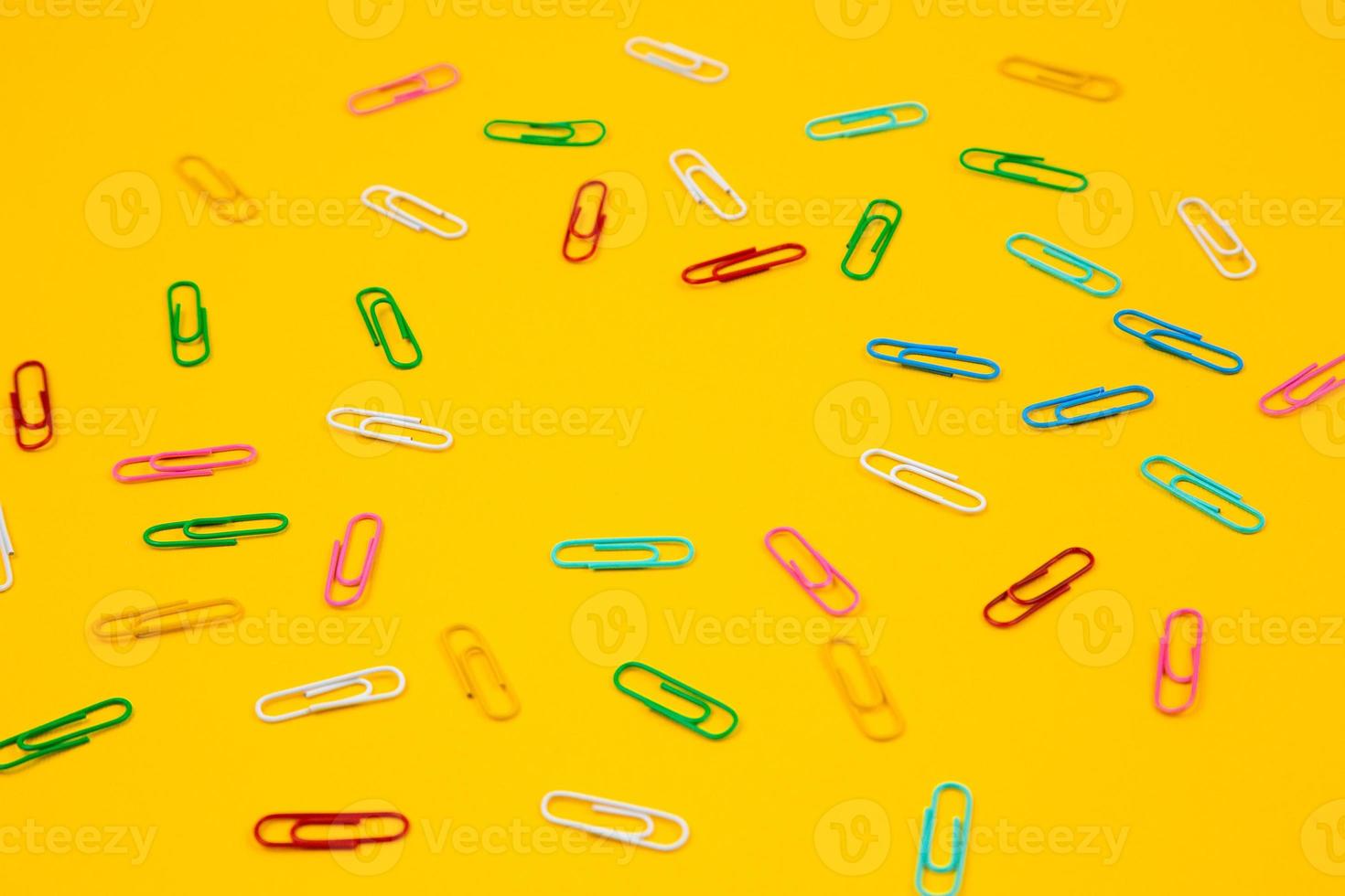 Colorful paper clips on yellow background photo