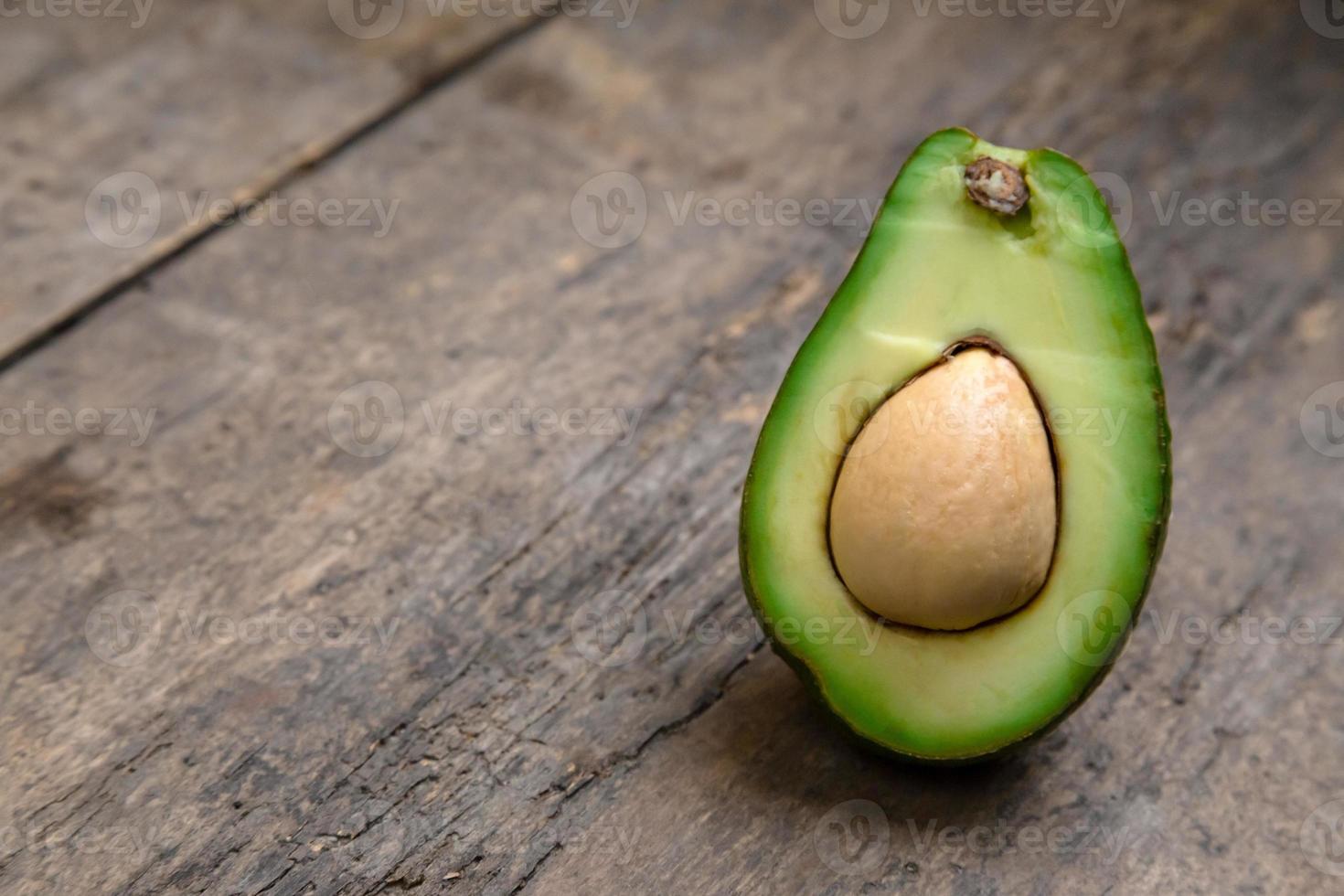 Aguacate fresco cortado por la mitad sobre una tabla de madera con fondo de cuchillo foto