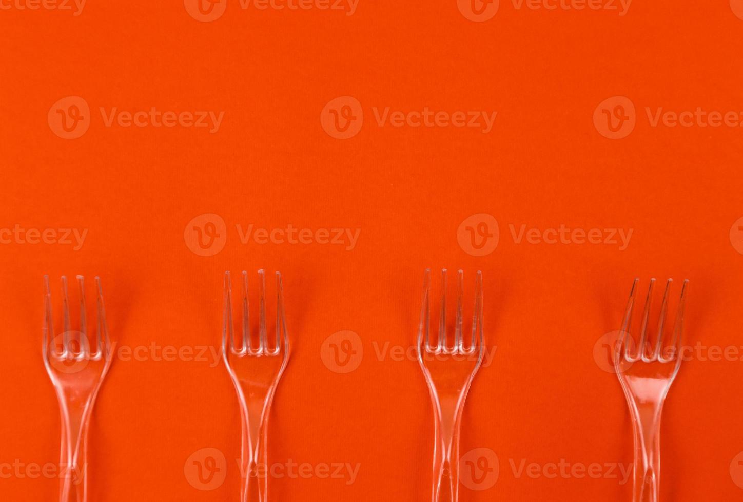 Close-up of clear plastic forks on an orange background photo