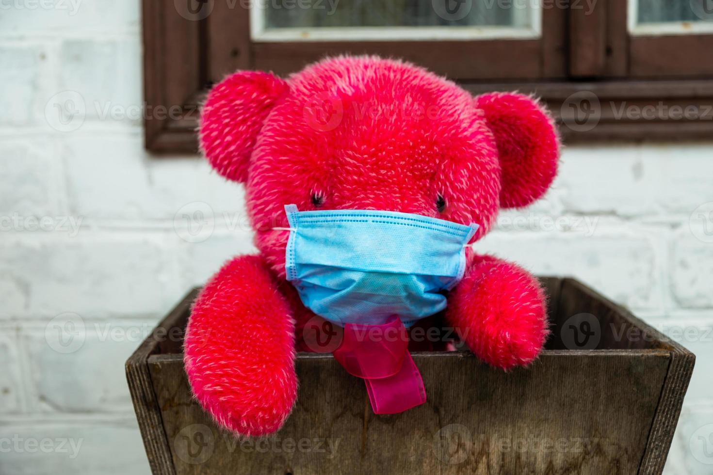 Lonely red teddy bear in a protective medical mask photo