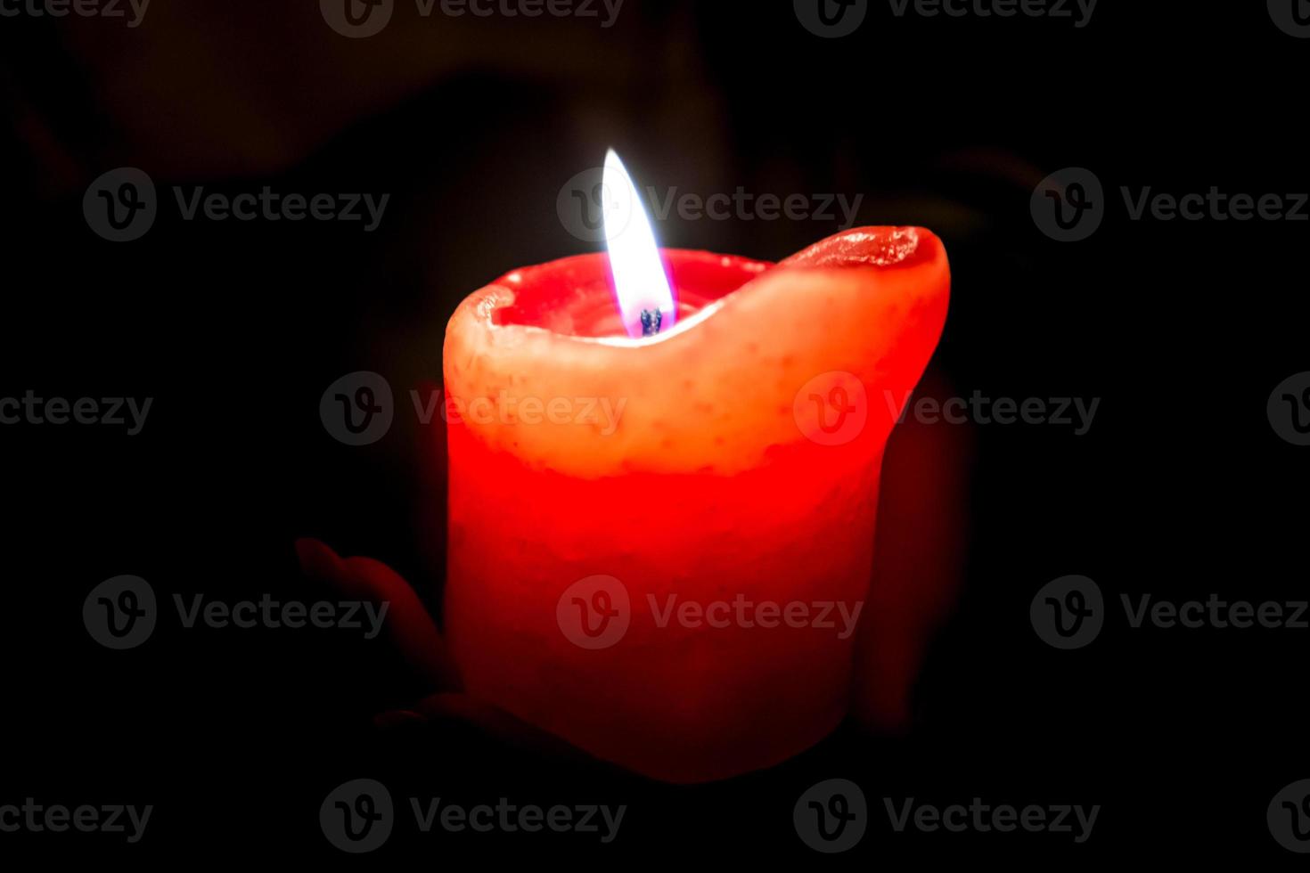 Female hands holding a burning candle in the darkness photo