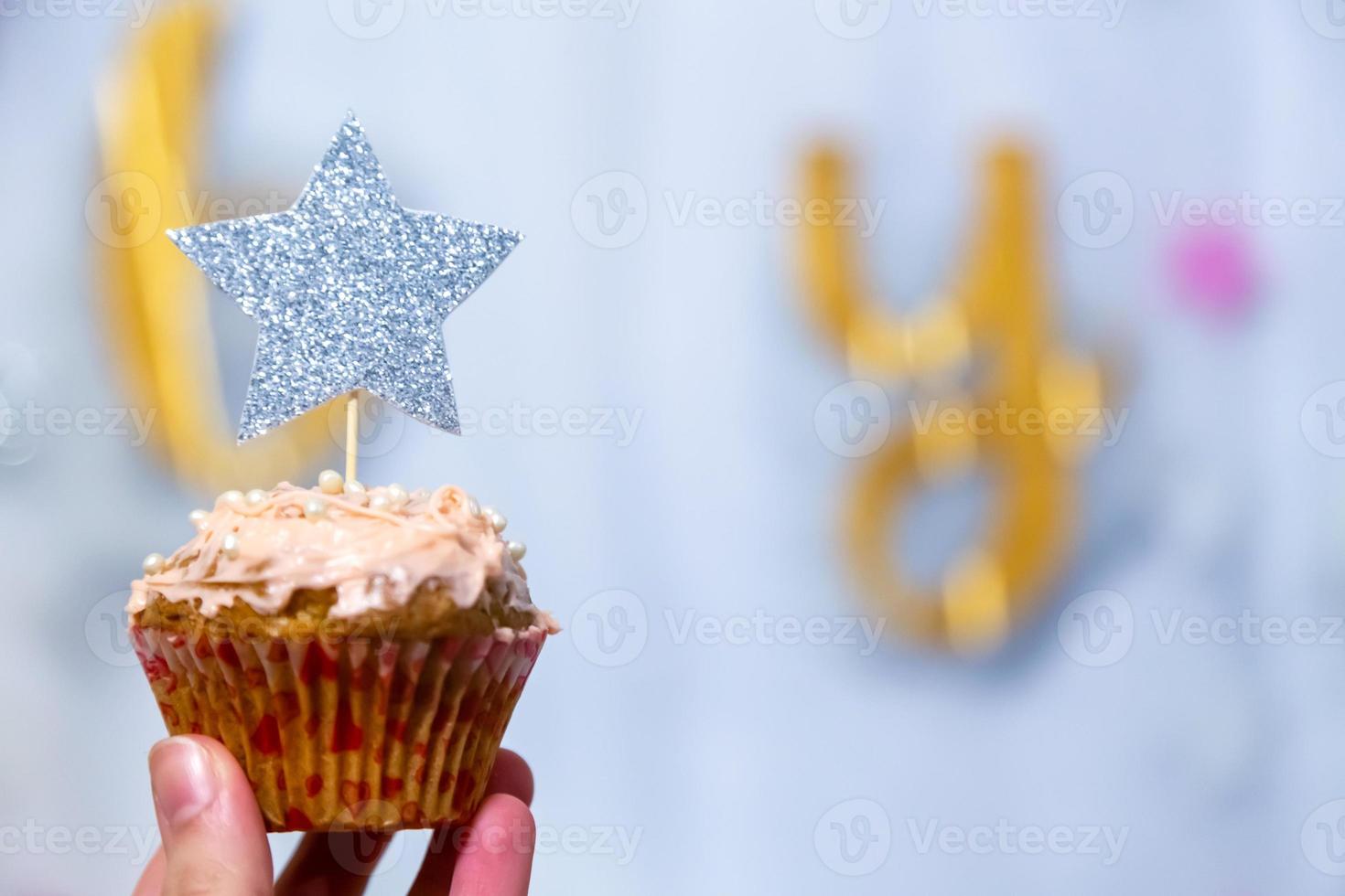 Girl hand holds cranberry cupcake with silver glitter star photo