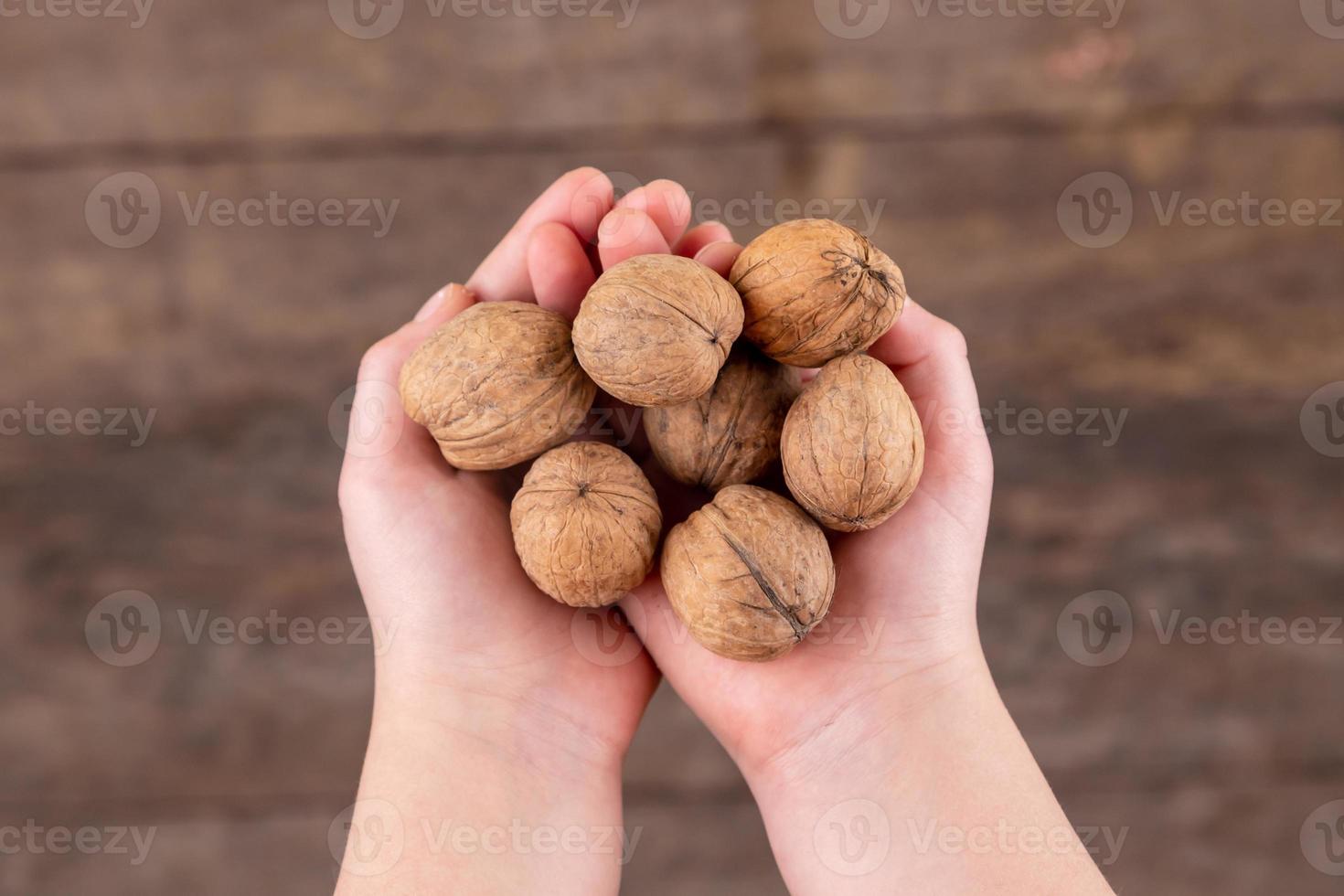 Fotografía cenital de manos de mujer sosteniendo nueces sobre mesa de madera foto