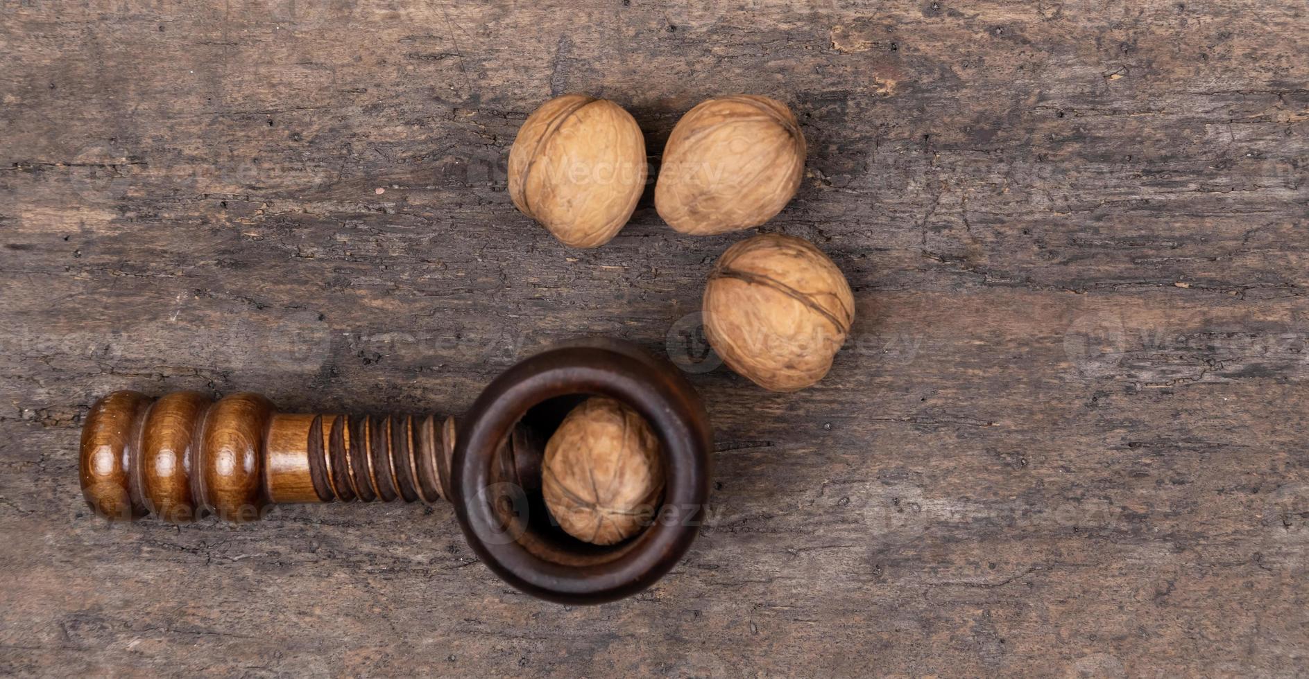 Organic walnuts with nut cracker on a wooden table wooden background photo