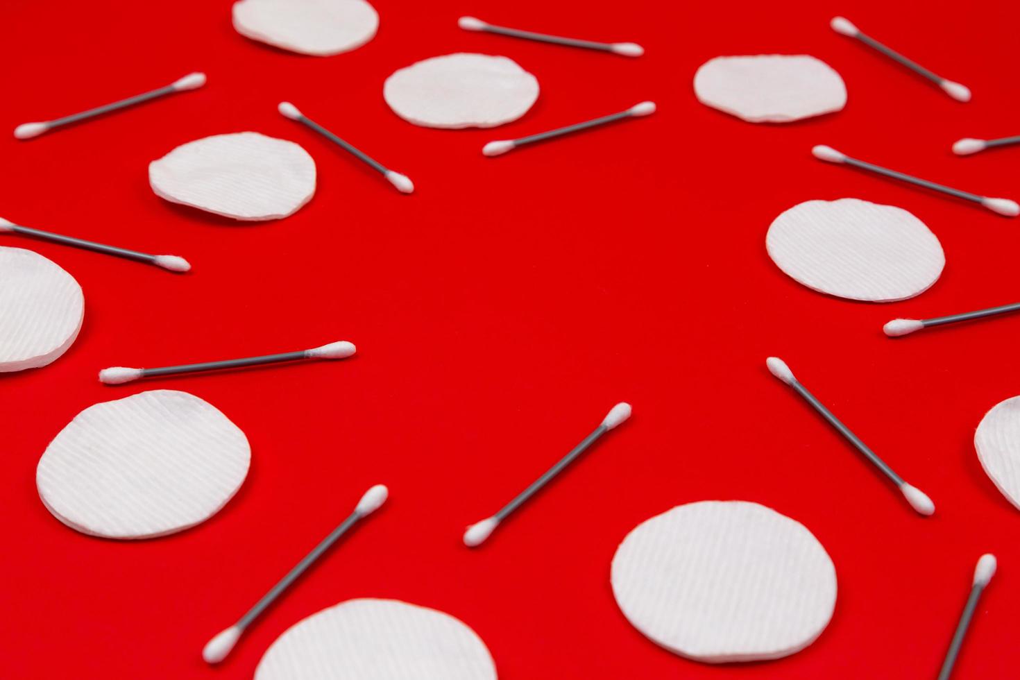 Cotton buds and cotton pads on a red background photo