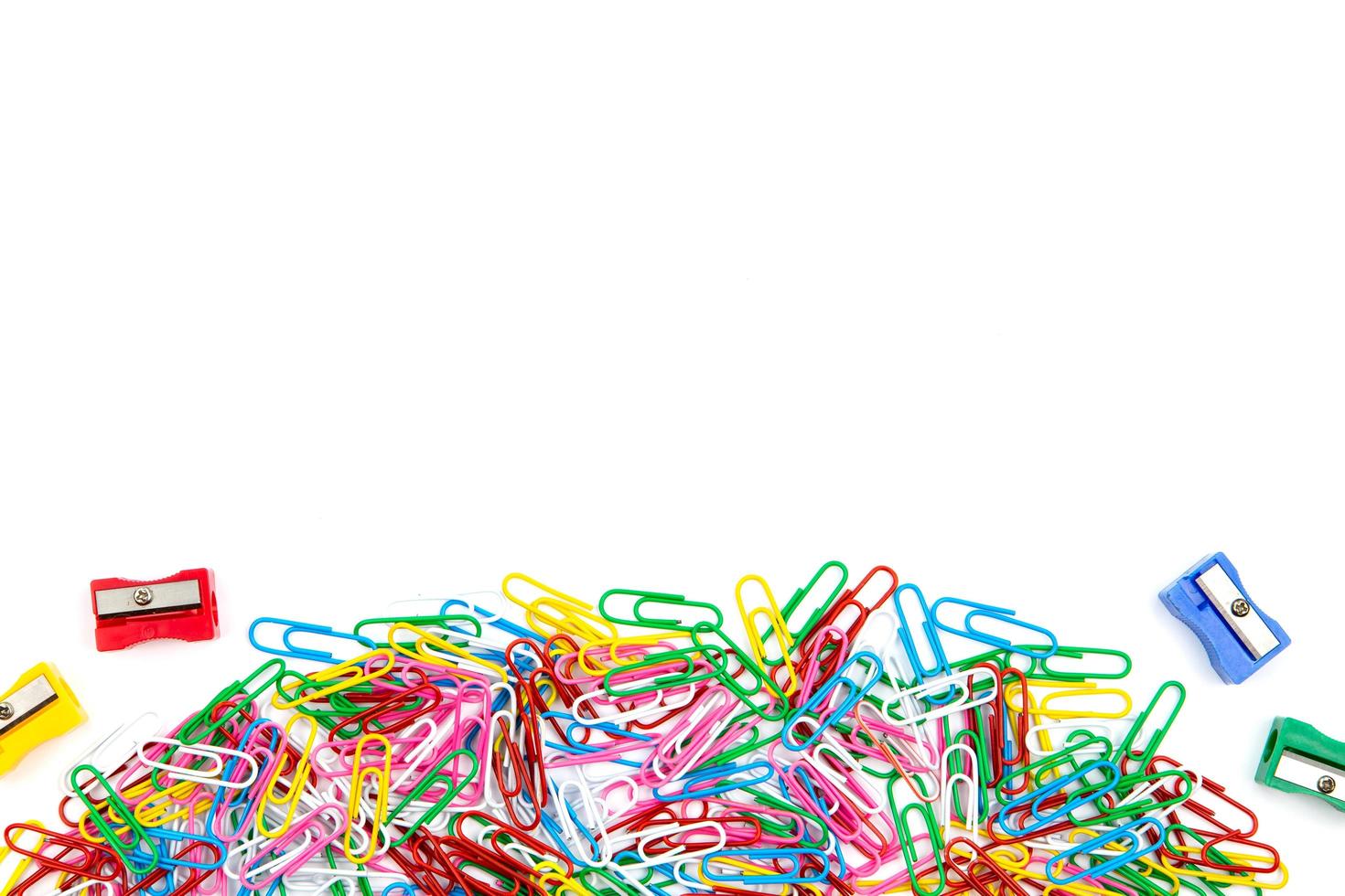 A lot of colored paper clips and pencil sharpeners on a white background photo